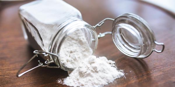 Borax Powder Spilling from a Glass Container on Wooden Table